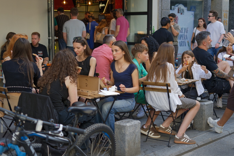 Street scene in Bucharest, featuring people gathered at outdoor cafe tables